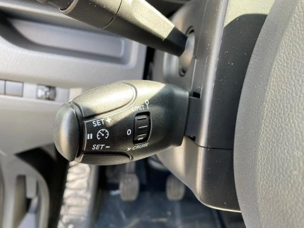 Gros plan sur la commande du régulateur de vitesse noire, côté gauche du volant du Peugeot Expert Fourgon blanc 2023.