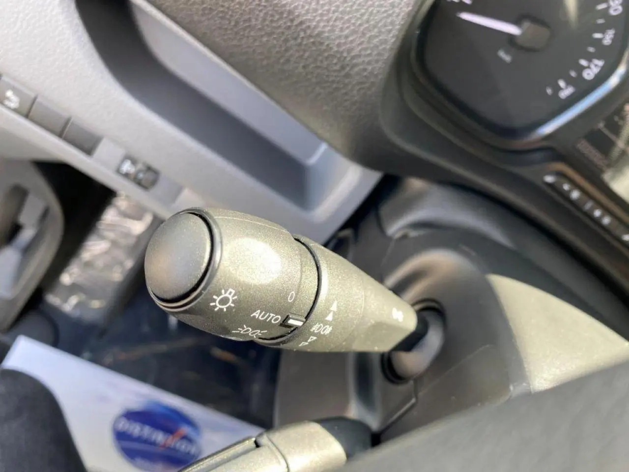 Gros plan sur la commande des phares du Peugeot Expert Fourgon blanc 2023, avec réglage automatique visible.