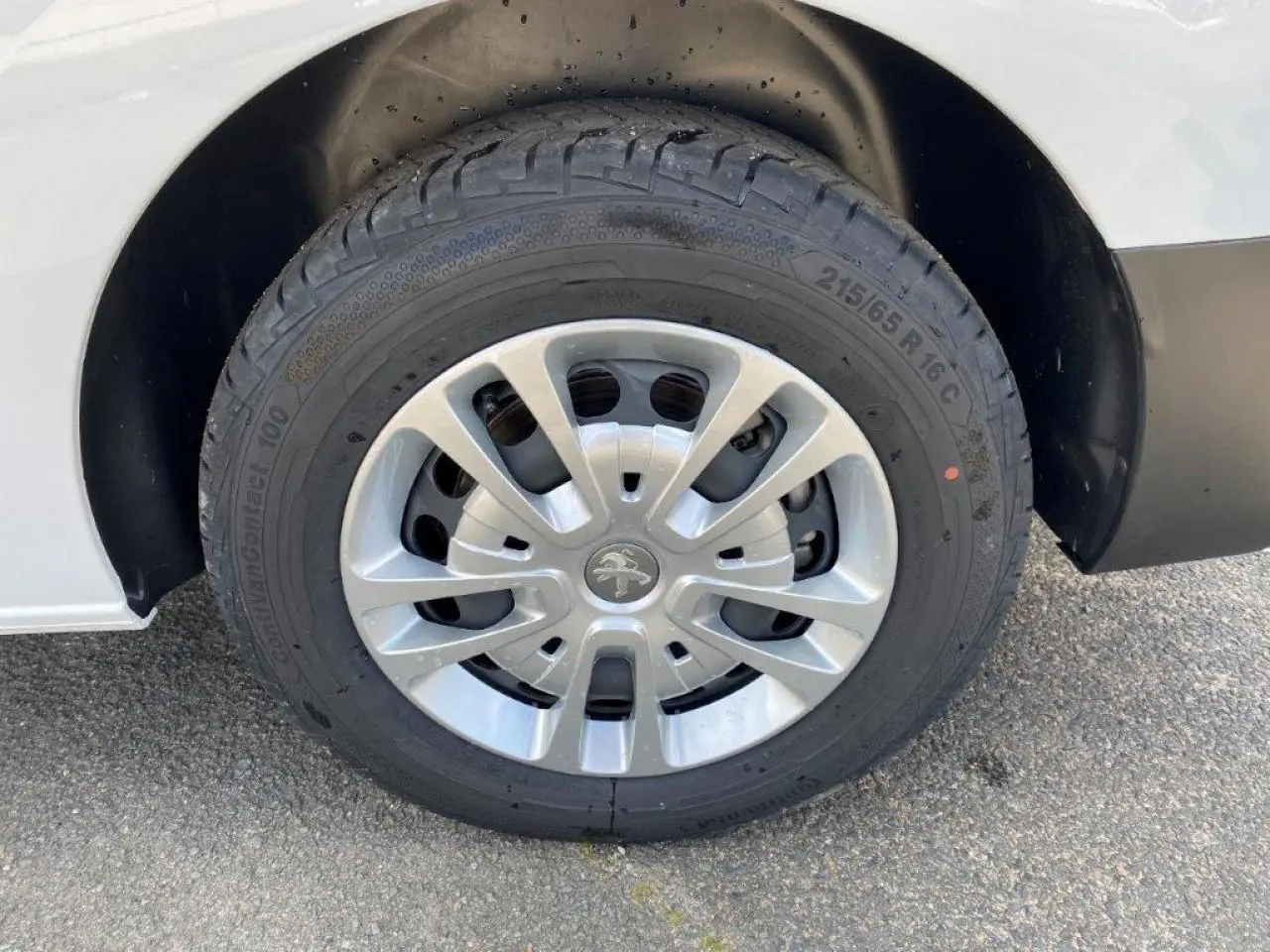 Gros plan sur la roue avant droite du Peugeot Expert Fourgon blanc 2023 avec jante en alliage et logo lion central.