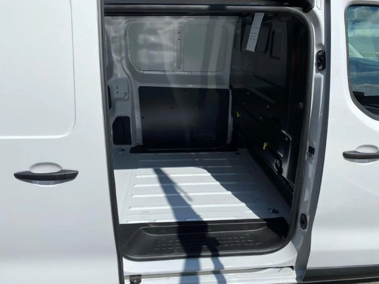 Vue intérieure du fourgon blanc Peugeot Expert Standard 2023, montrant l'espace de chargement côté droit avec porte coulissante ouverte.