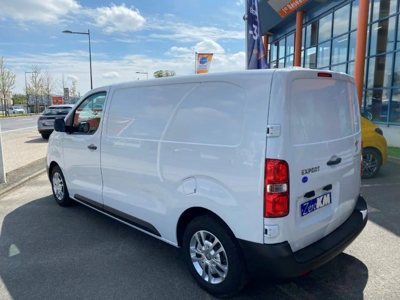 Vue 3/4 arrière droite d'un fourgon blanc Peugeot Expert avec porte latérale coulissante et jantes alliage.