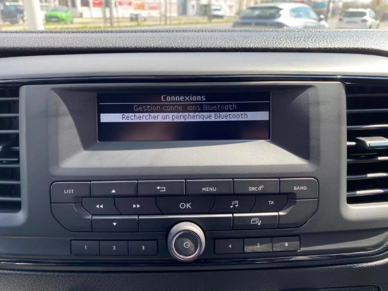 Gros plan sur la console centrale du Peugeot Expert Fourgon blanc 2023, affichant la recherche Bluetooth sur l'écran digital.