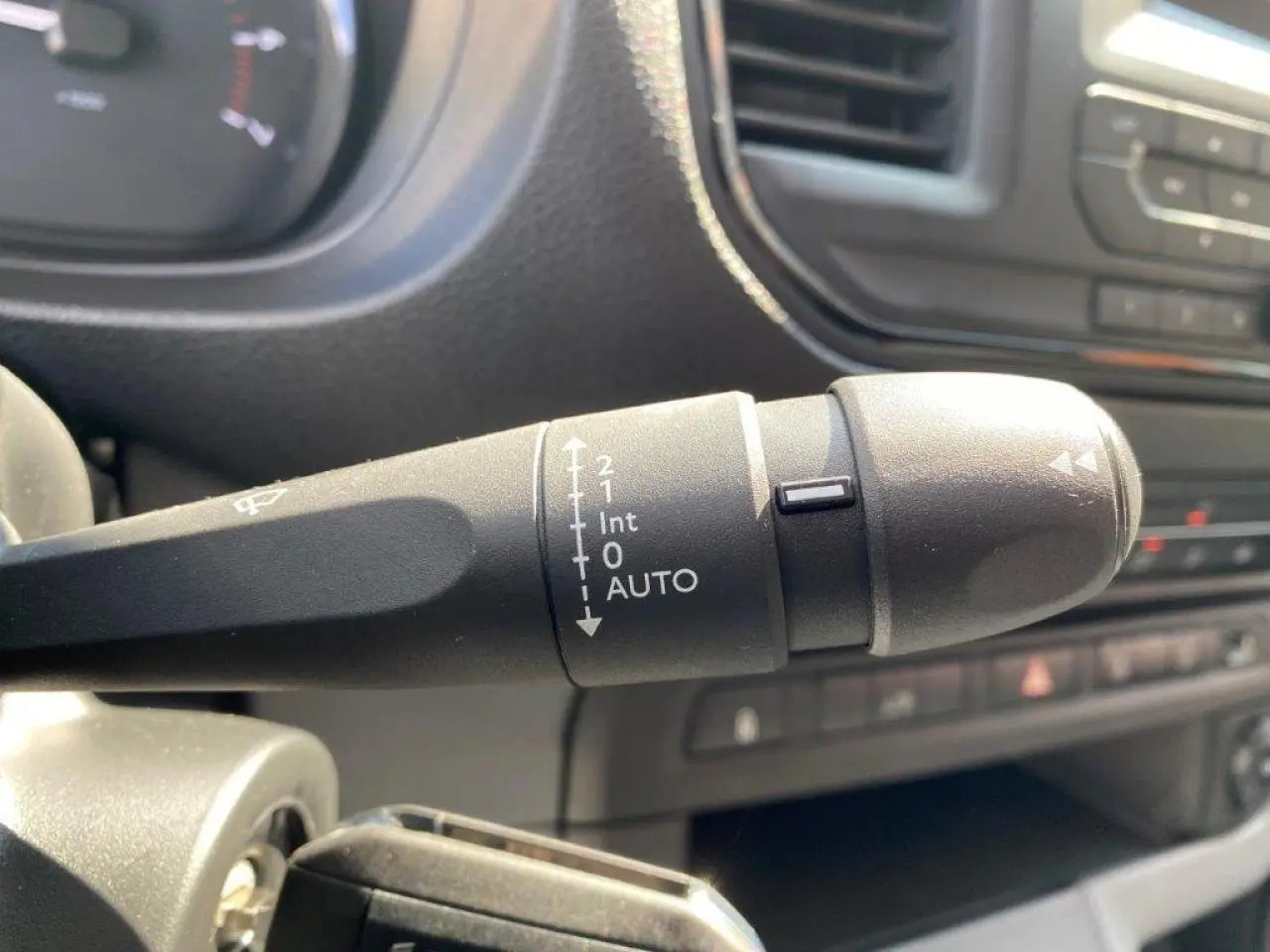 Gros plan sur la commande d'essuie-glace automatique du Peugeot Expert Fourgon blanc, tableau de bord en arrière-plan.