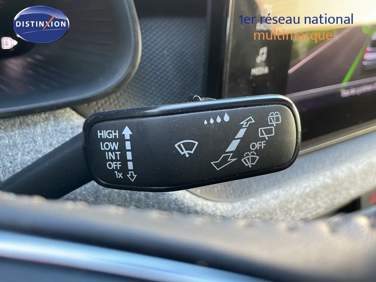 Gros plan sur le commodo d’essuie-glace du Skoda Kamiq noir magique métal 2024, avec commandes visibles et tableau de bord flou.