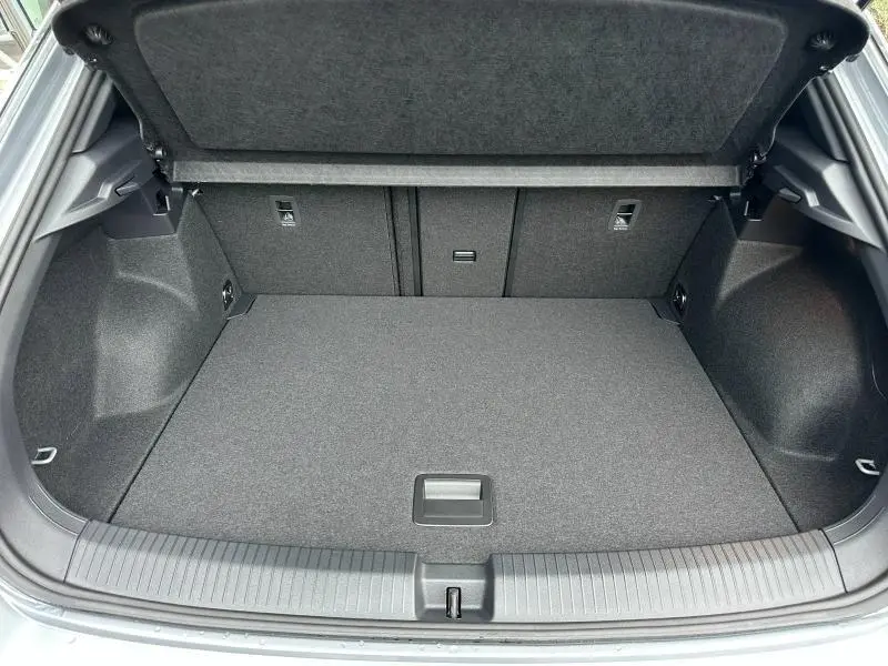 Coffre ouvert vu de l'arrière d'un Volkswagen T-Roc gris 2025, version R-Line avec intérieur de coffre propre et spacieux.