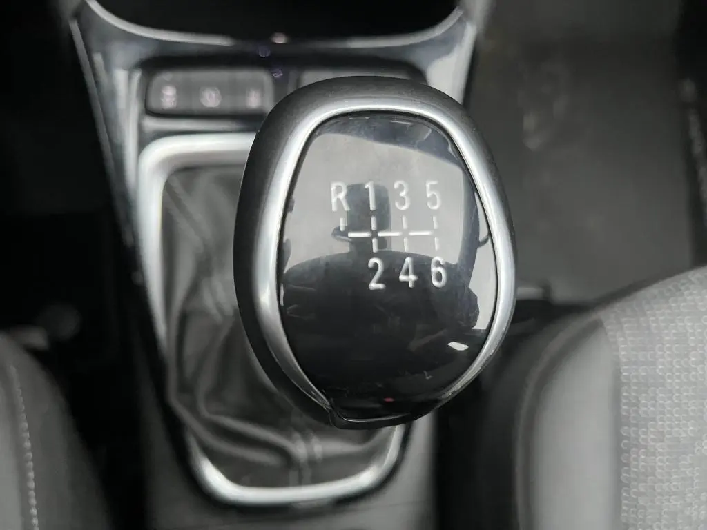 Gros plan sur le levier de vitesses manuel noir de l'Opel Crossland 1.2i Turbo Edition, intérieur sombre.