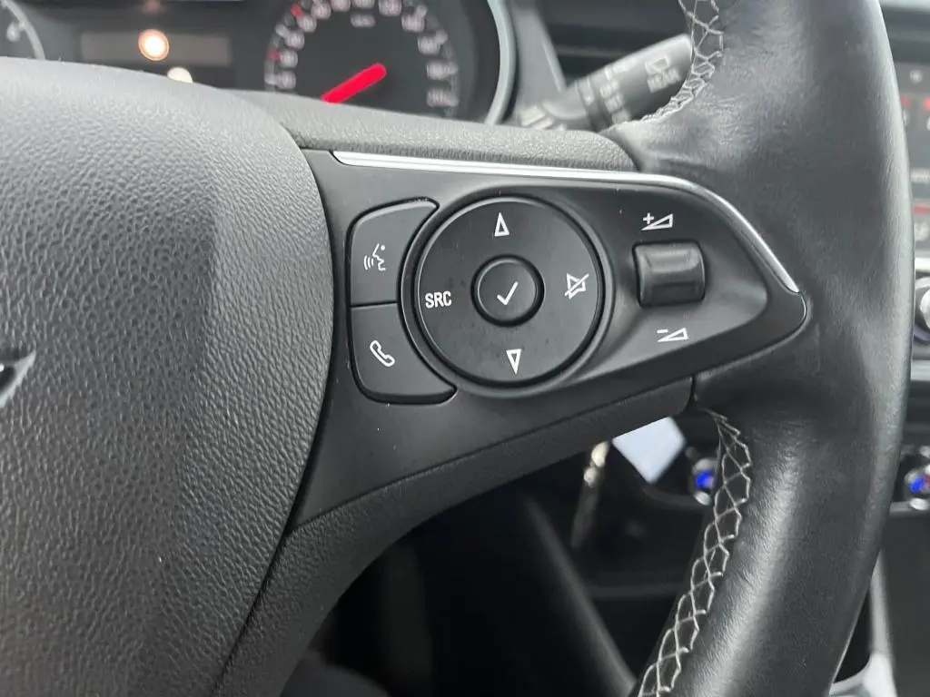 Gros plan sur les commandes au volant noir de l'Opel Crossland bleu clair 2021, avec boutons de volume et appels.