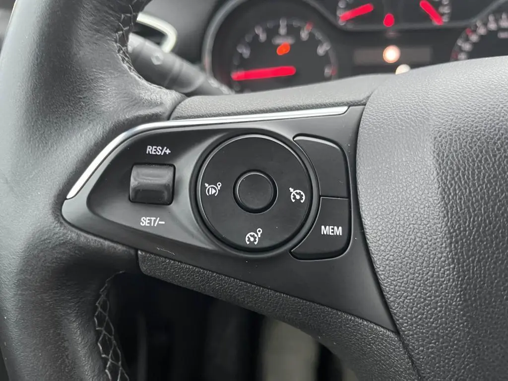 Gros plan sur les commandes de régulateur de vitesse au volant noir de l'Opel Crossland bleu clair 2021.