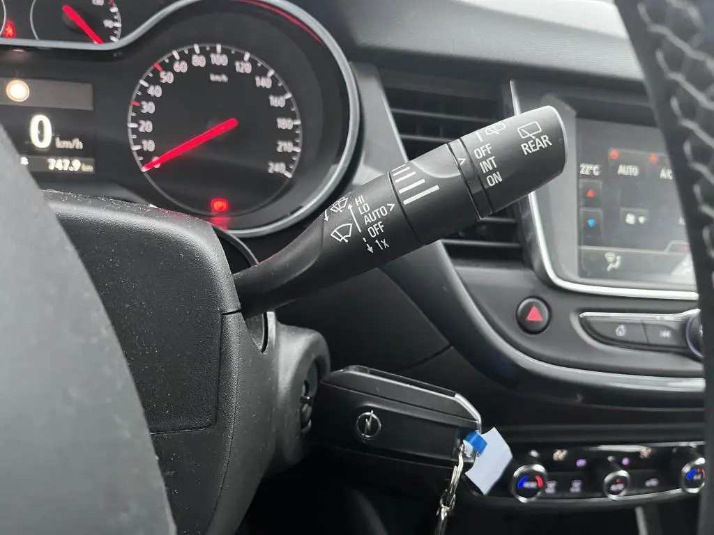 Gros plan sur le commodo d'essuie-glace à gauche du volant dans l'habitacle noir de l'Opel Crossland bleu clair 2021.