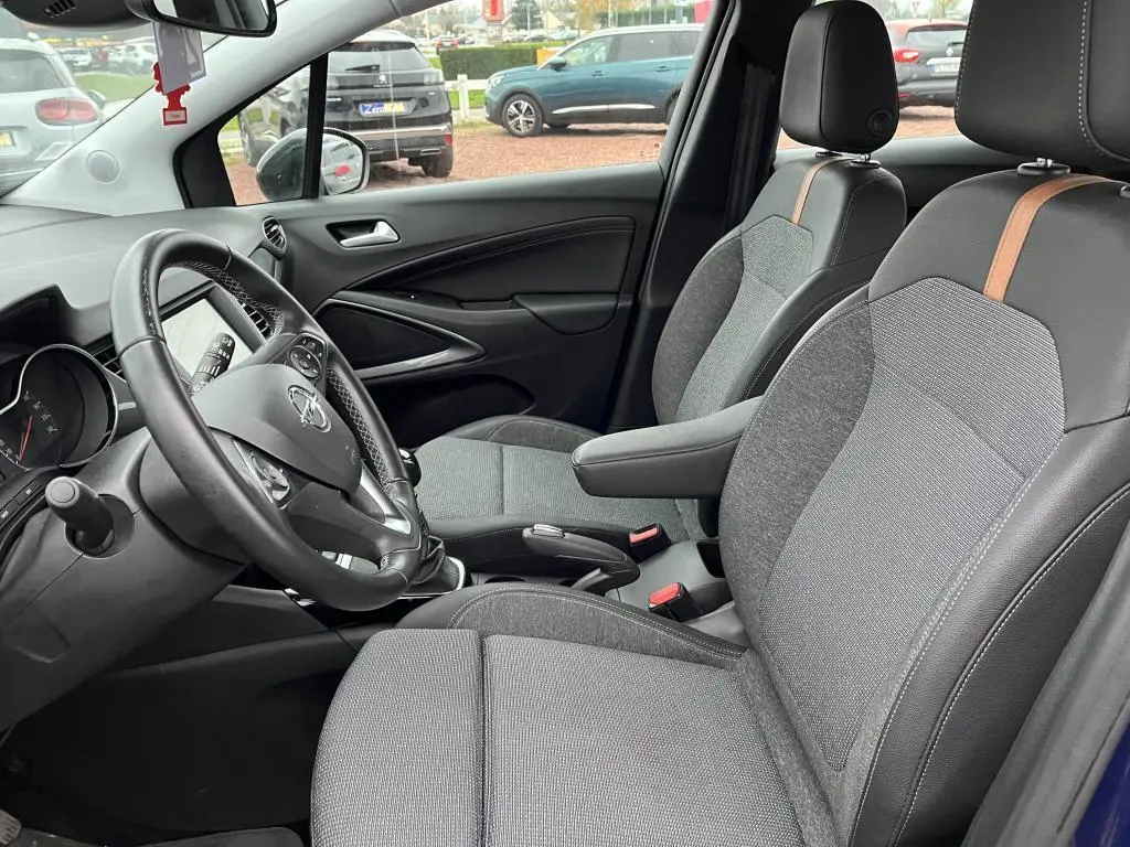 Vue intérieure côté conducteur de l'Opel Crossland 2021, sièges gris avec bande orange et volant multifonction.