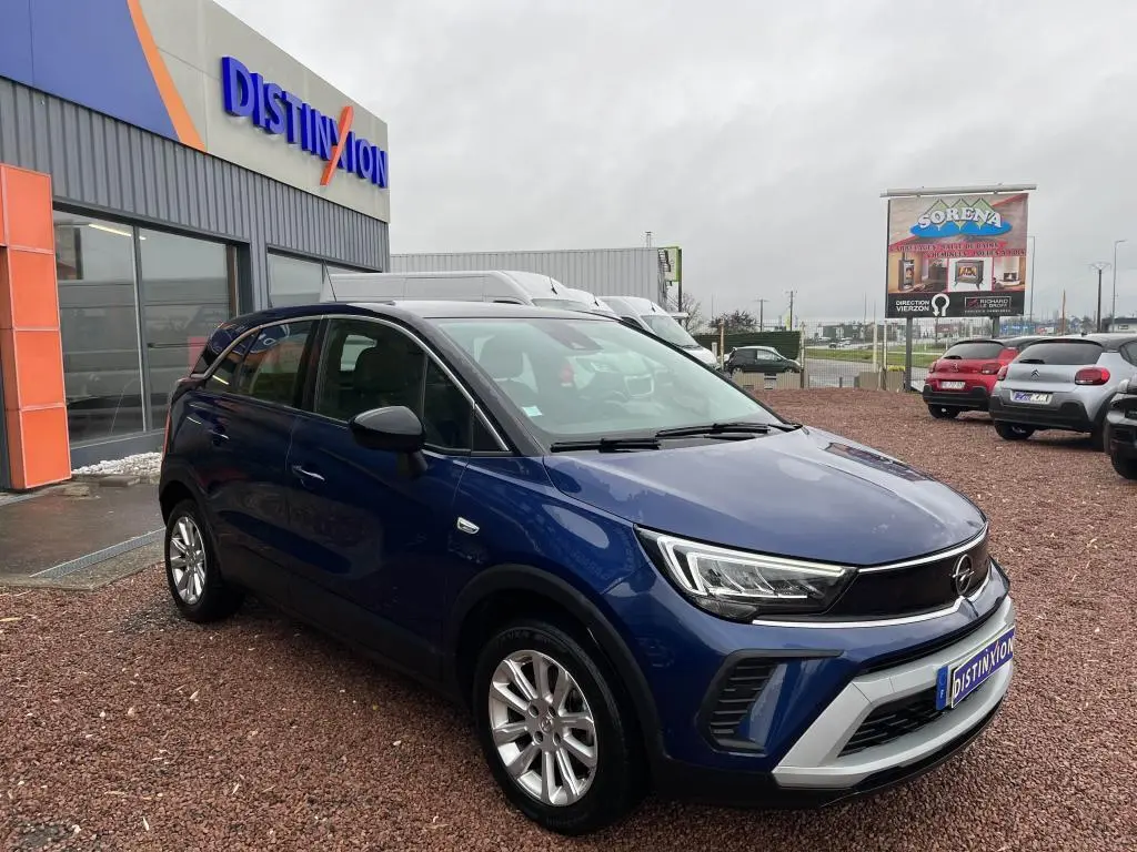 Opel Crossland bleu clair vue 3/4 avant droit avec toit noir garée devant un bâtiment commercial