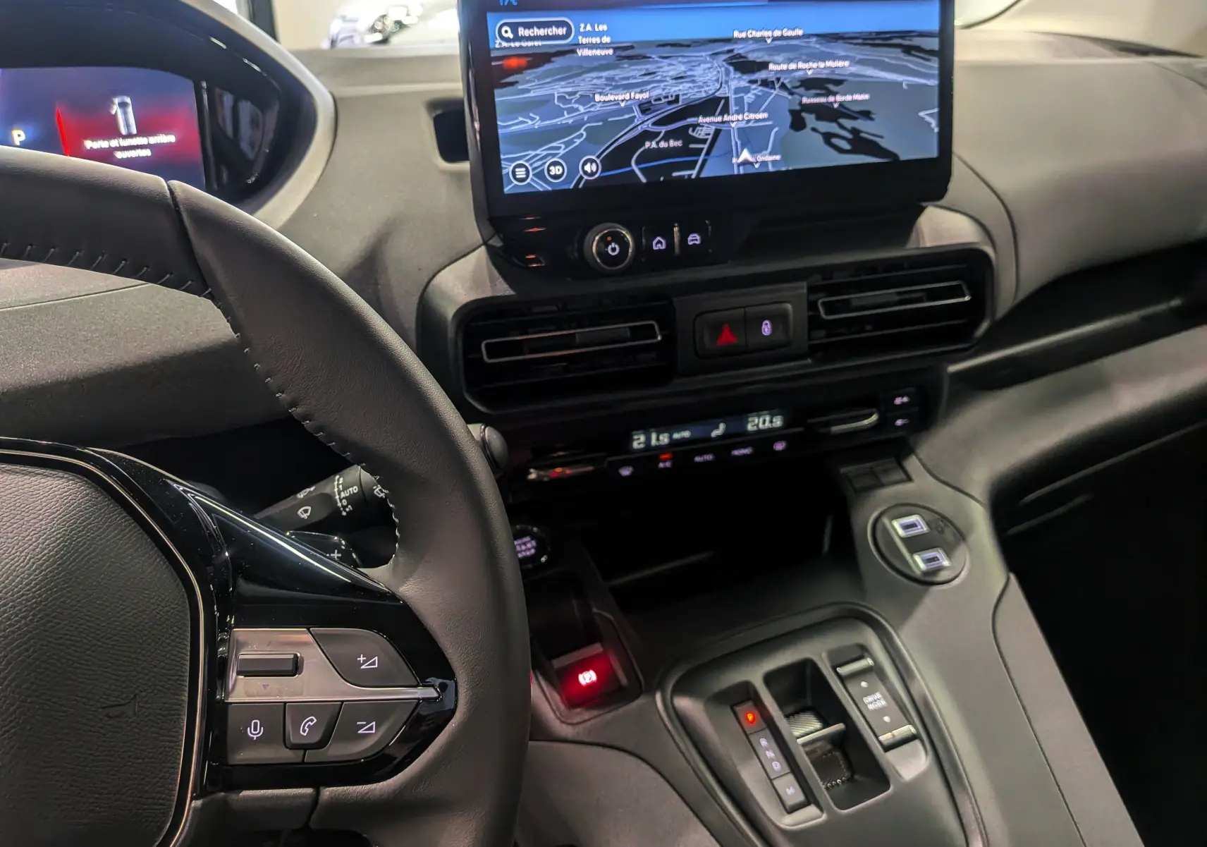 Vue intérieure du Peugeot Rifter 2025 noir, focus sur le volant, la console centrale avec écran tactile et commandes de climatisation.