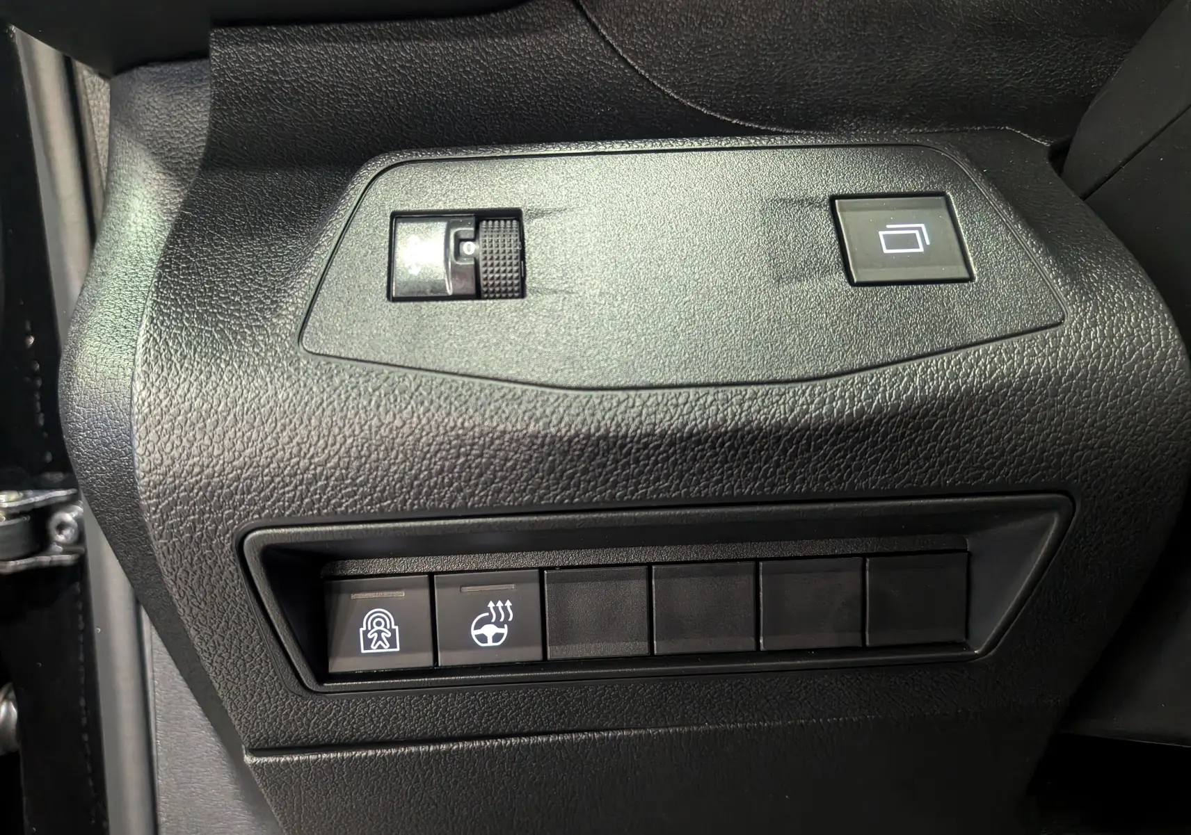 Gros plan sur les commandes noires du tableau de bord côté gauche du Peugeot Rifter noir 2025, avec boutons chauffants et verrouillage.