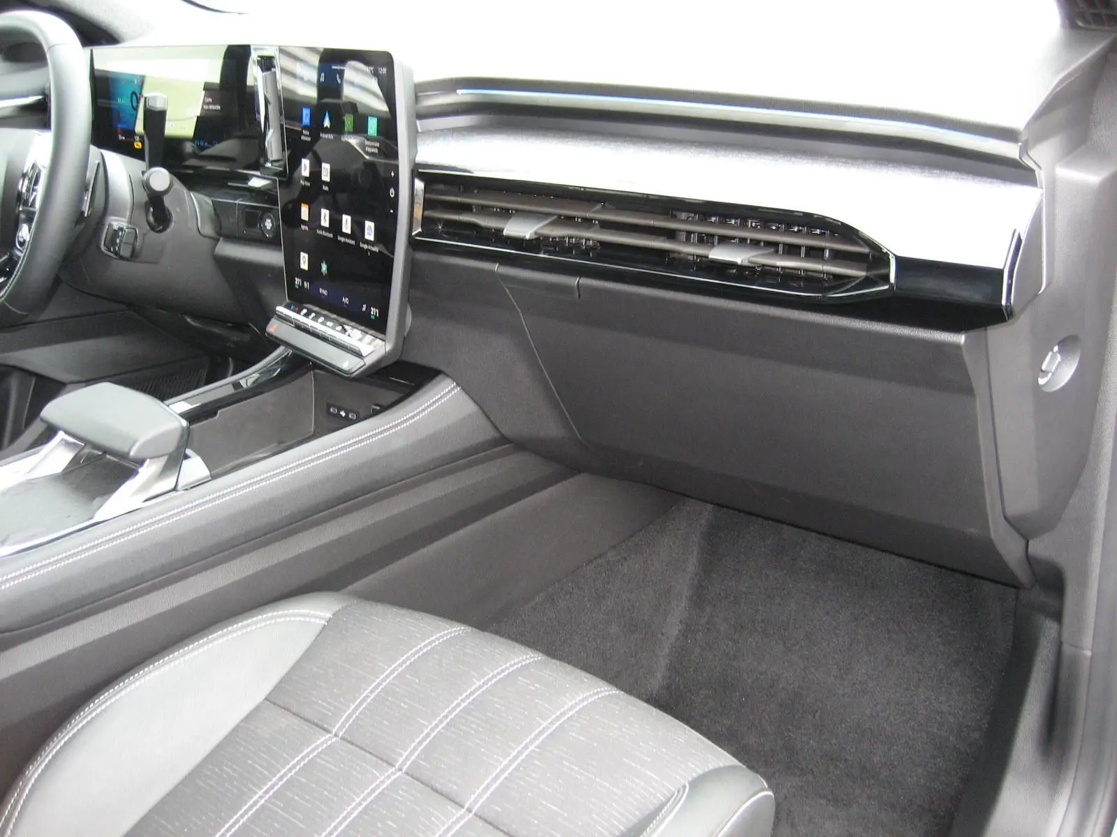 Vue intérieure côté passager du Renault Austral gris 2025, mettant en valeur la console centrale et l'écran tactile vertical.