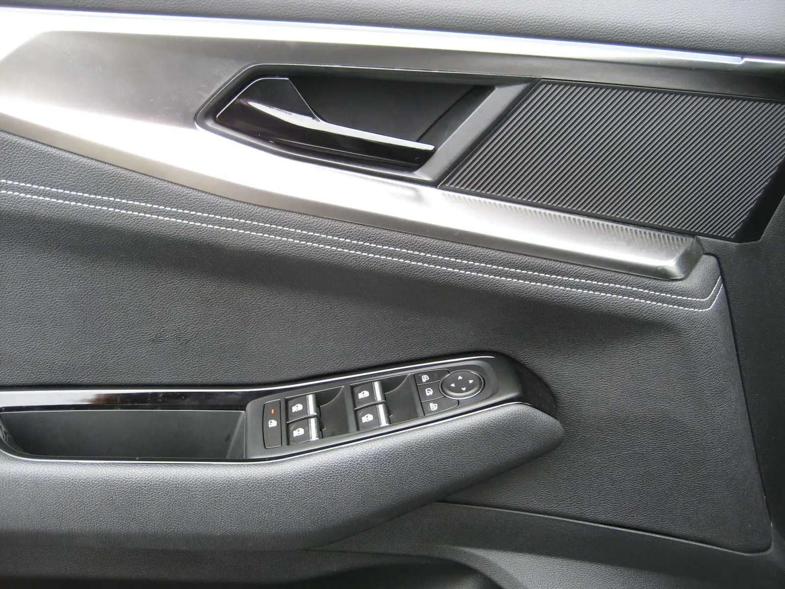 Détail de la porte côté gauche du Renault Austral gris 2025, montrant les commandes des vitres et la poignée intérieure.