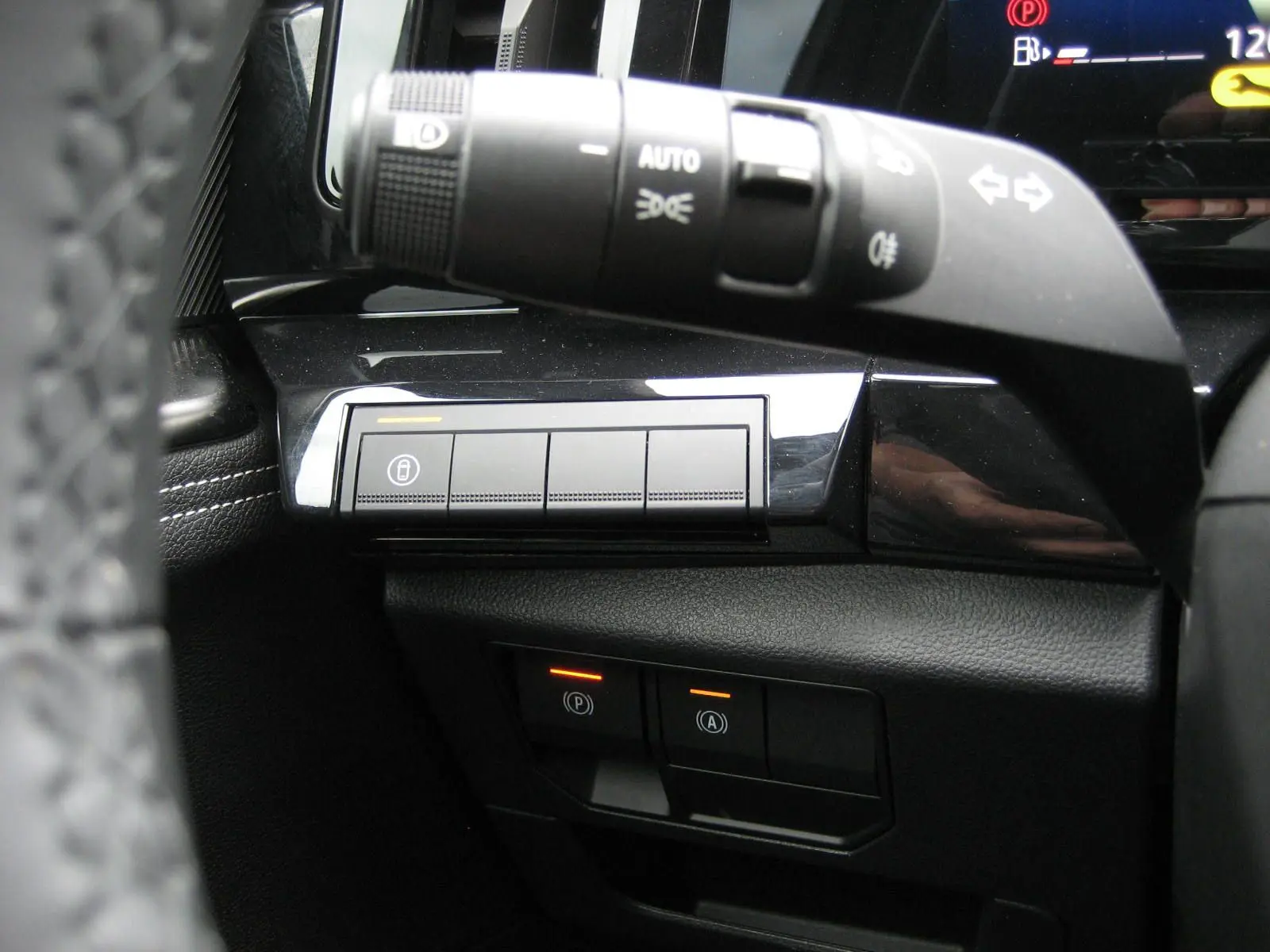 Gros plan sur la commande des feux et les boutons de sécurité du tableau de bord d’un Renault Austral gris 2025.