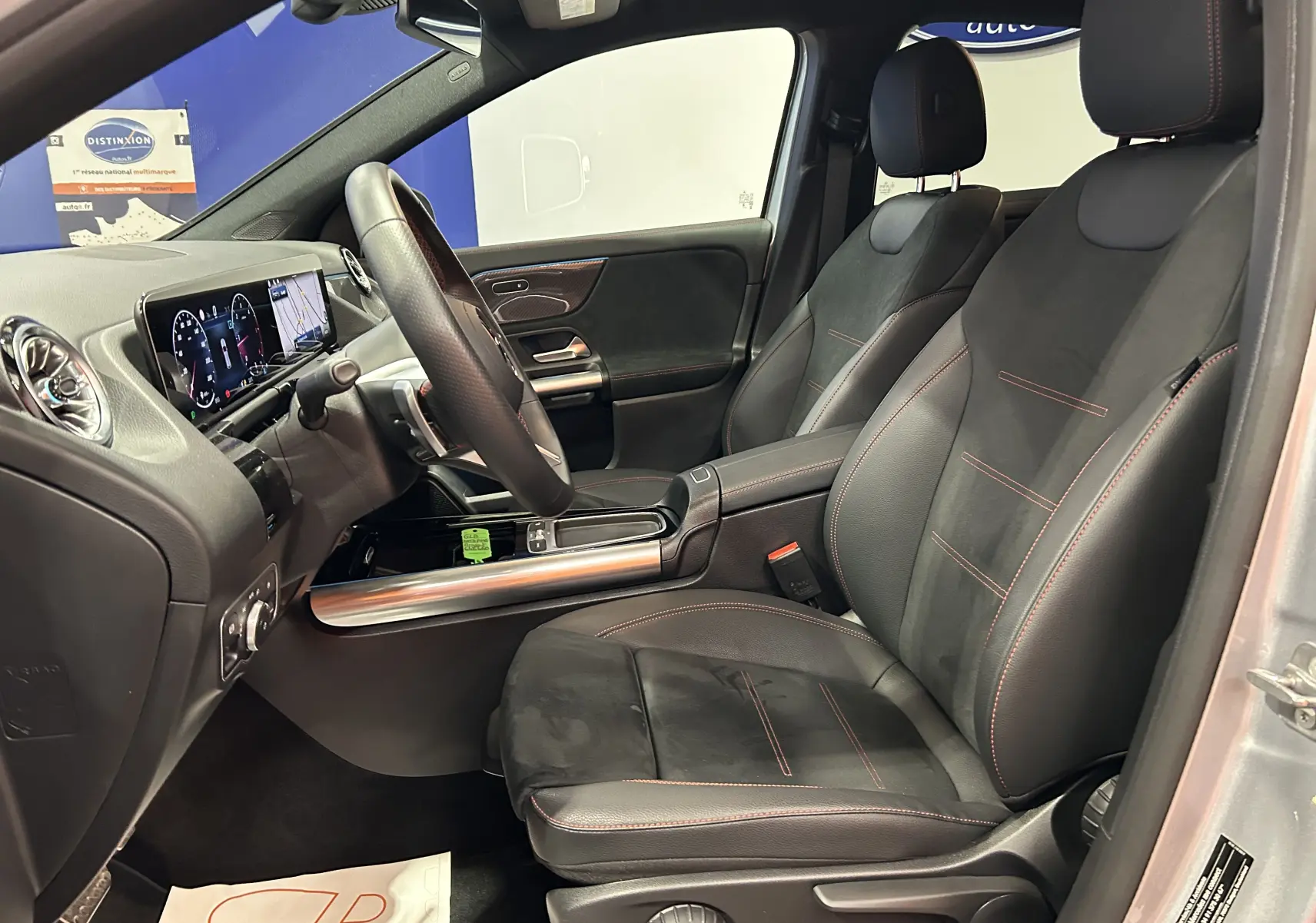 Intérieur noir avec surpiqûres rouges du Mercedes GLA 200 D AMG Line 2024, vue côté conducteur ouverte sur tableau de bord digital.