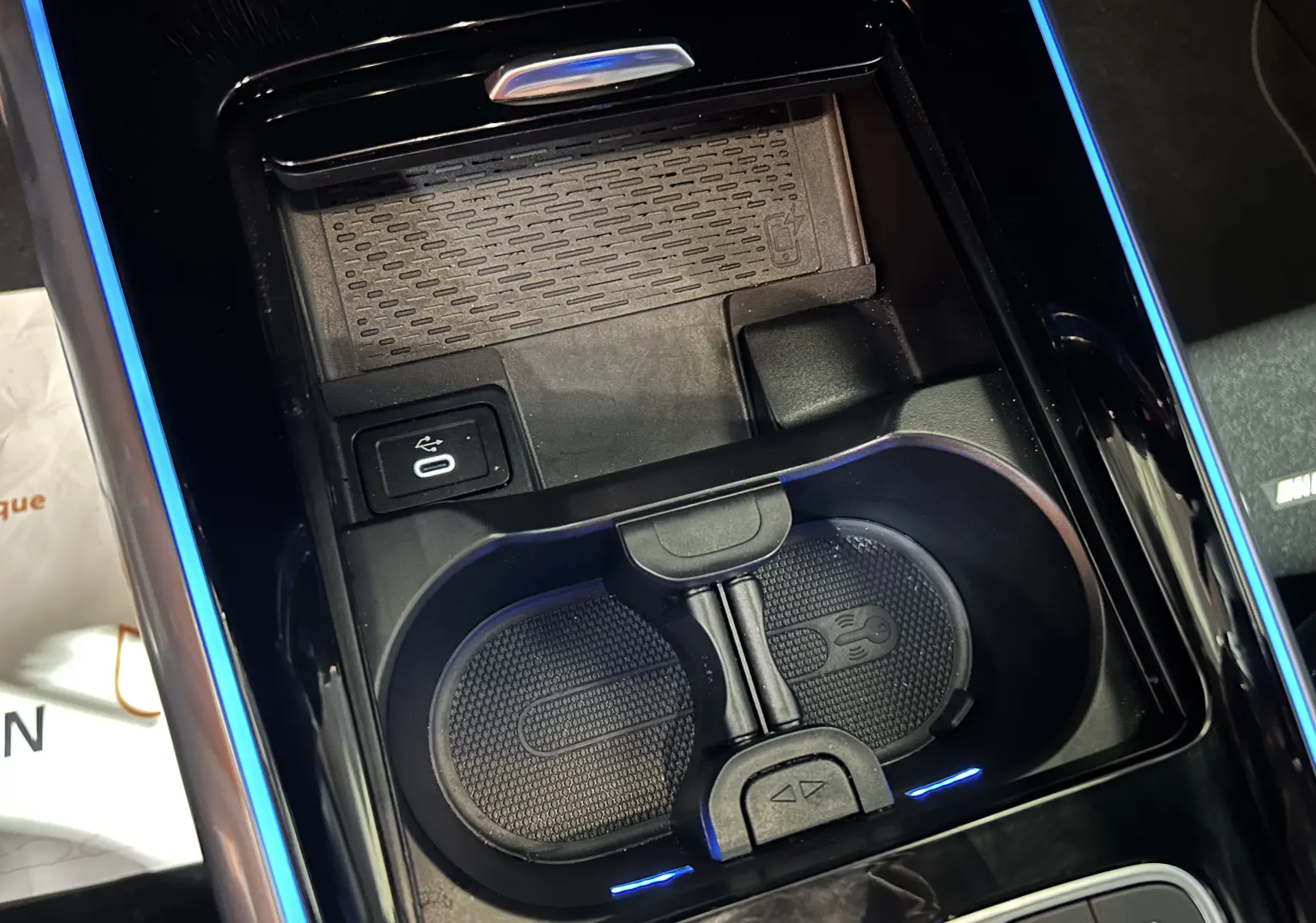 Gros plan sur la console centrale noire avec porte-gobelets et chargeur sans fil du Mercedes GLA 200 D AMG Line argent High-tech.