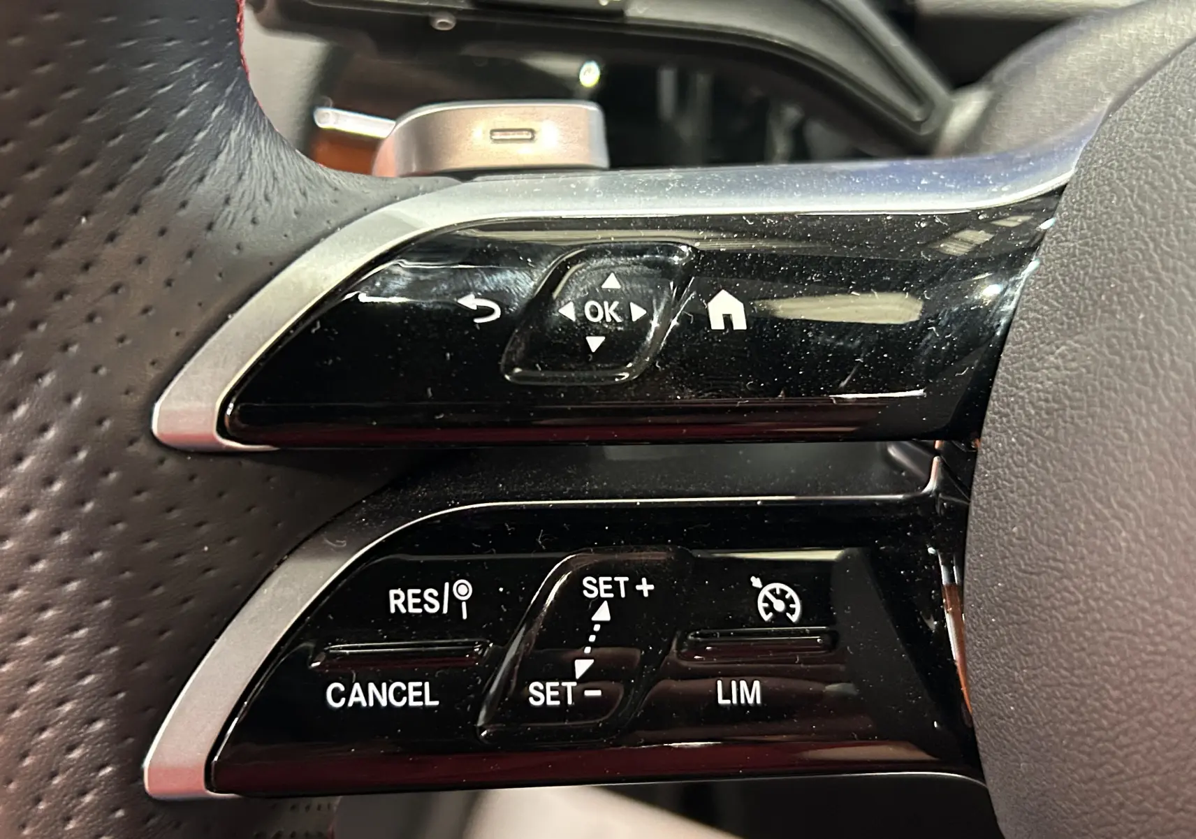 Gros plan sur les commandes au volant noir et argent du Mercedes GLA 200 D AMG Line 2024, finition sportive