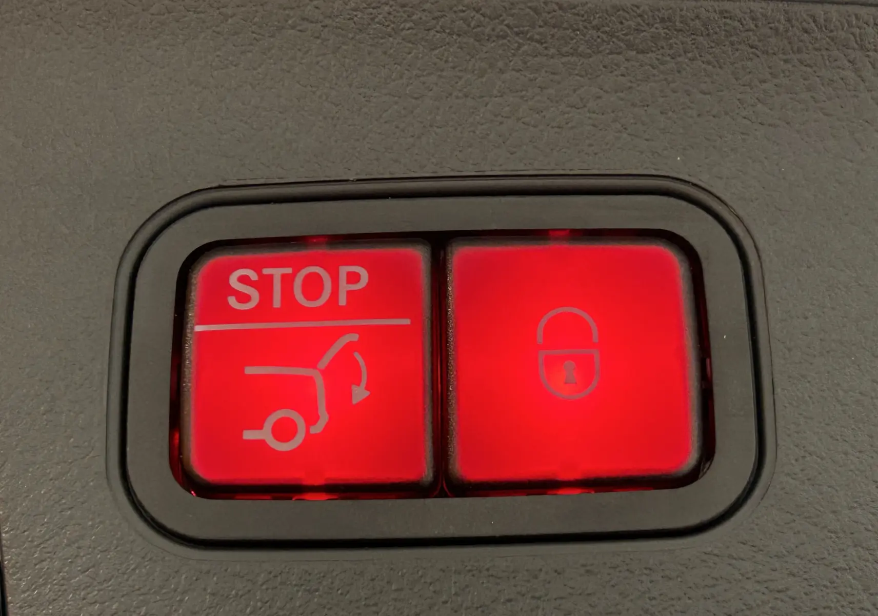 Boutons rouges d'ouverture et de verrouillage du hayon sur la console intérieure d'une Mercedes GLA argent High-tech 2024.