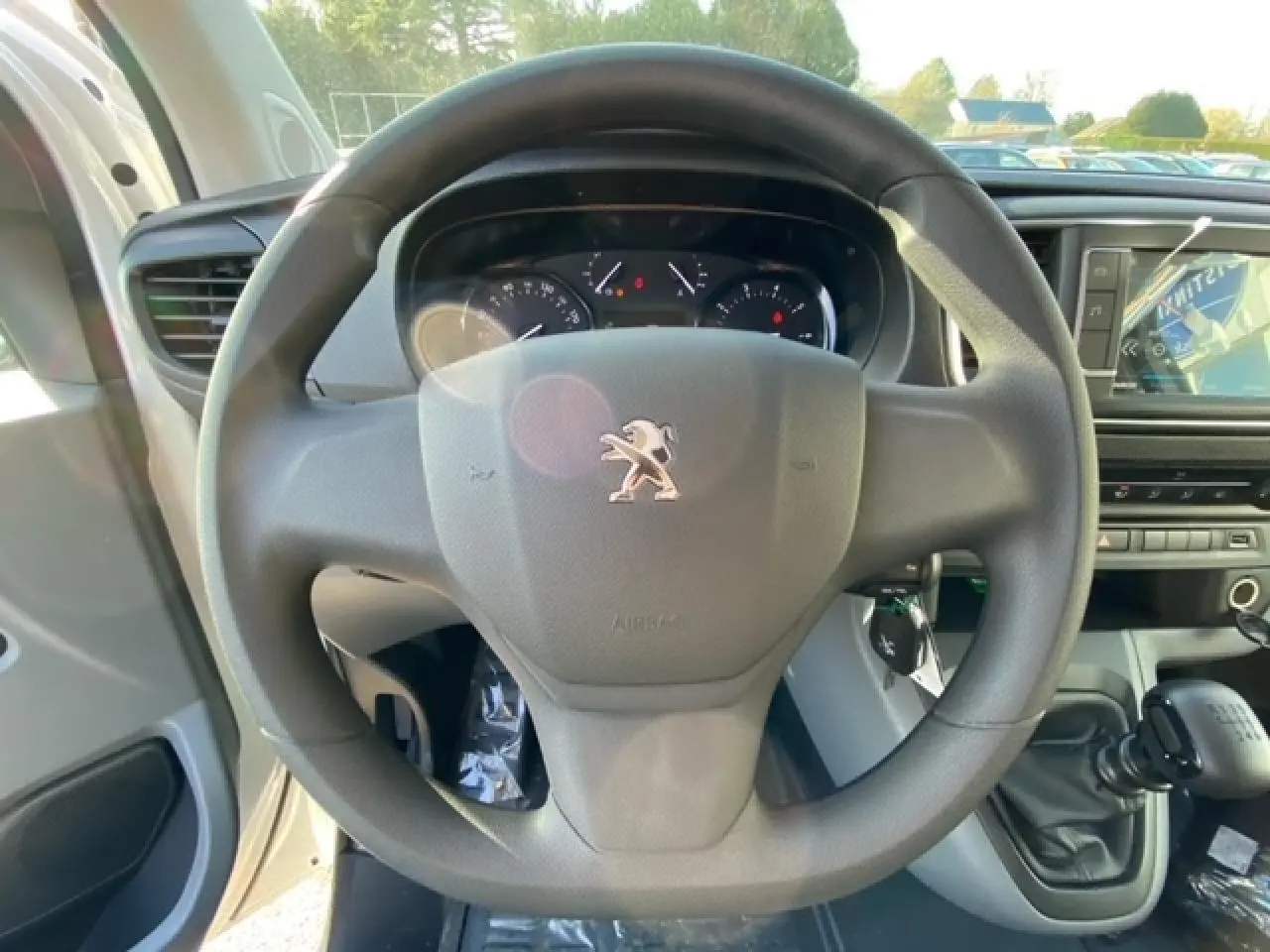 Vue rapprochée du volant Peugeot Expert Fourgon blanc banquise 2023 avec tableau de bord et levier de vitesses manuel visible.