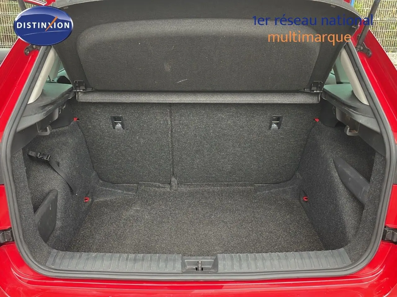 Coffre ouvert d'un Skoda Kamiq rouge Velvet Metal, montrant l'espace de chargement intérieur en tissu gris.