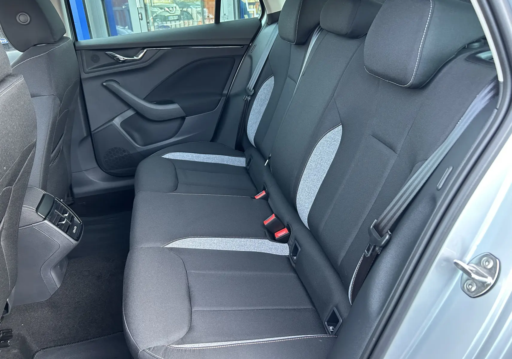 Vue latérale droite de l'intérieur arrière du Skoda Kamiq 2025, sièges tissu noir et gris avec surpiqûres blanches.