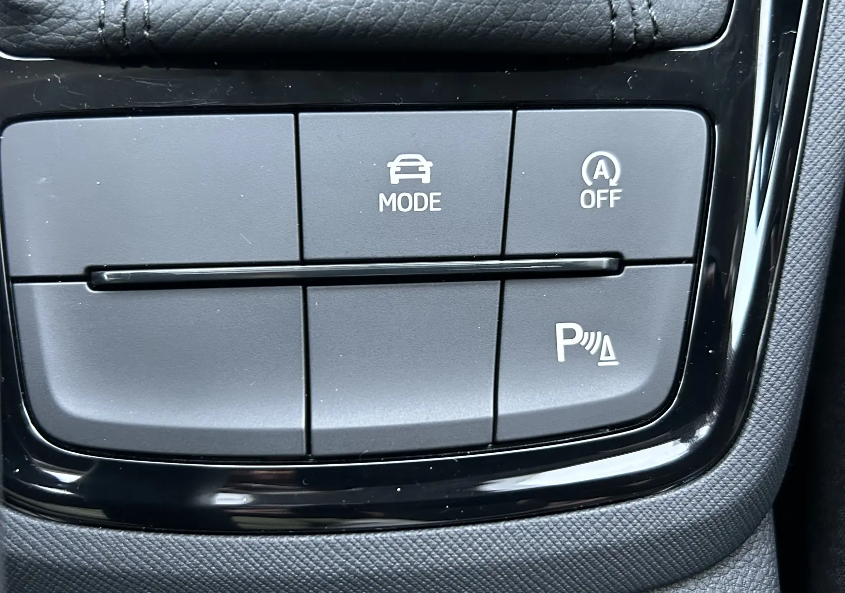 Gros plan sur les boutons de commande du mode de conduite et assistance au stationnement dans une Skoda Kamiq gris argent 2025.