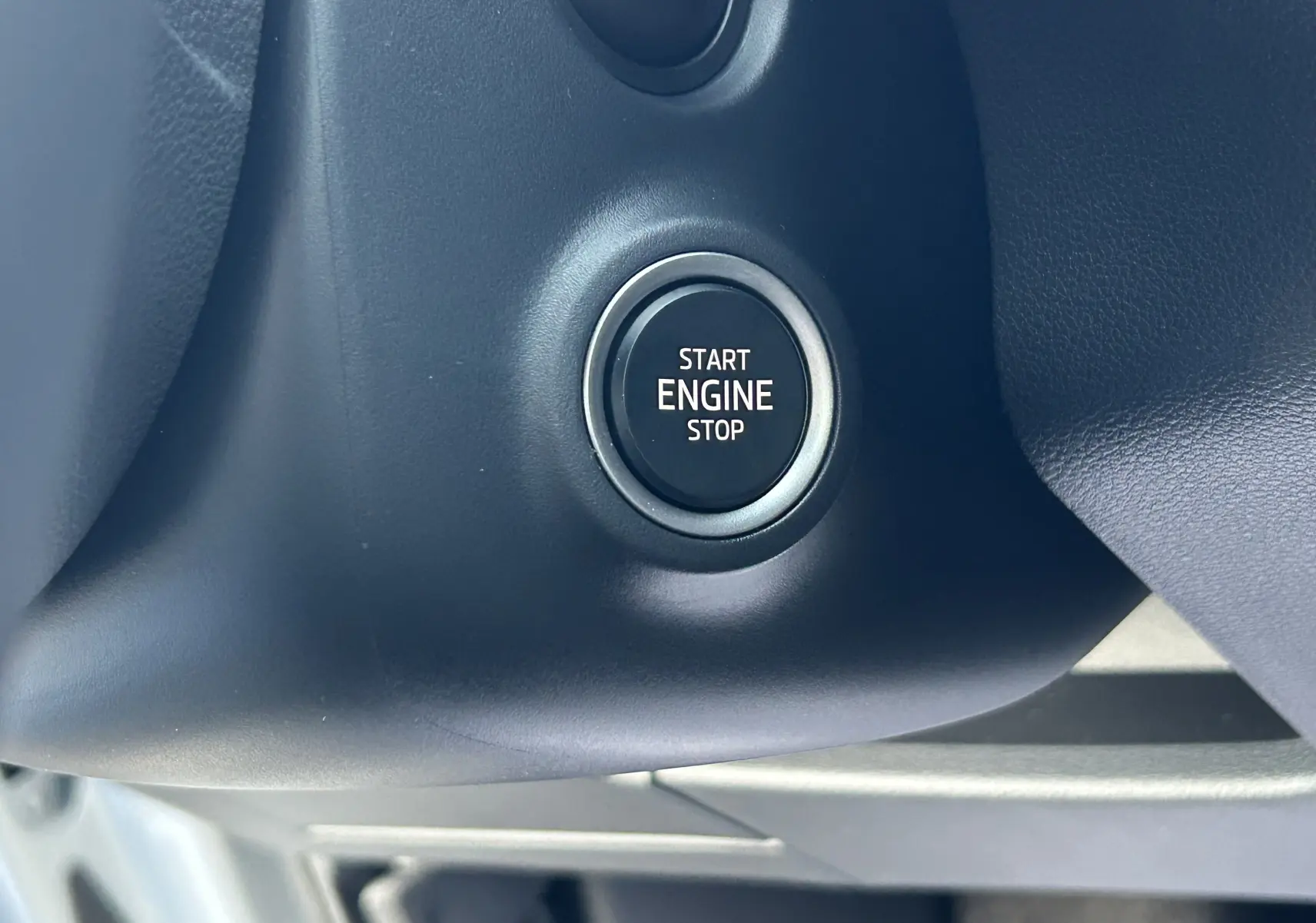 Gros plan sur le bouton Start Engine Stop noir entouré de gris dans l'habitacle du Skoda Kamiq 2025 gris argent.