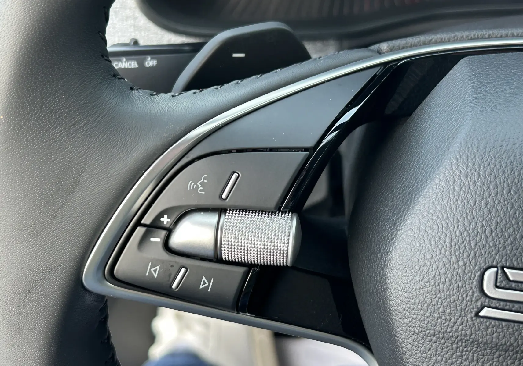 Gros plan sur la molette de réglage du volume et les commandes vocales au volant du Skoda Kamiq gris argent 2025.