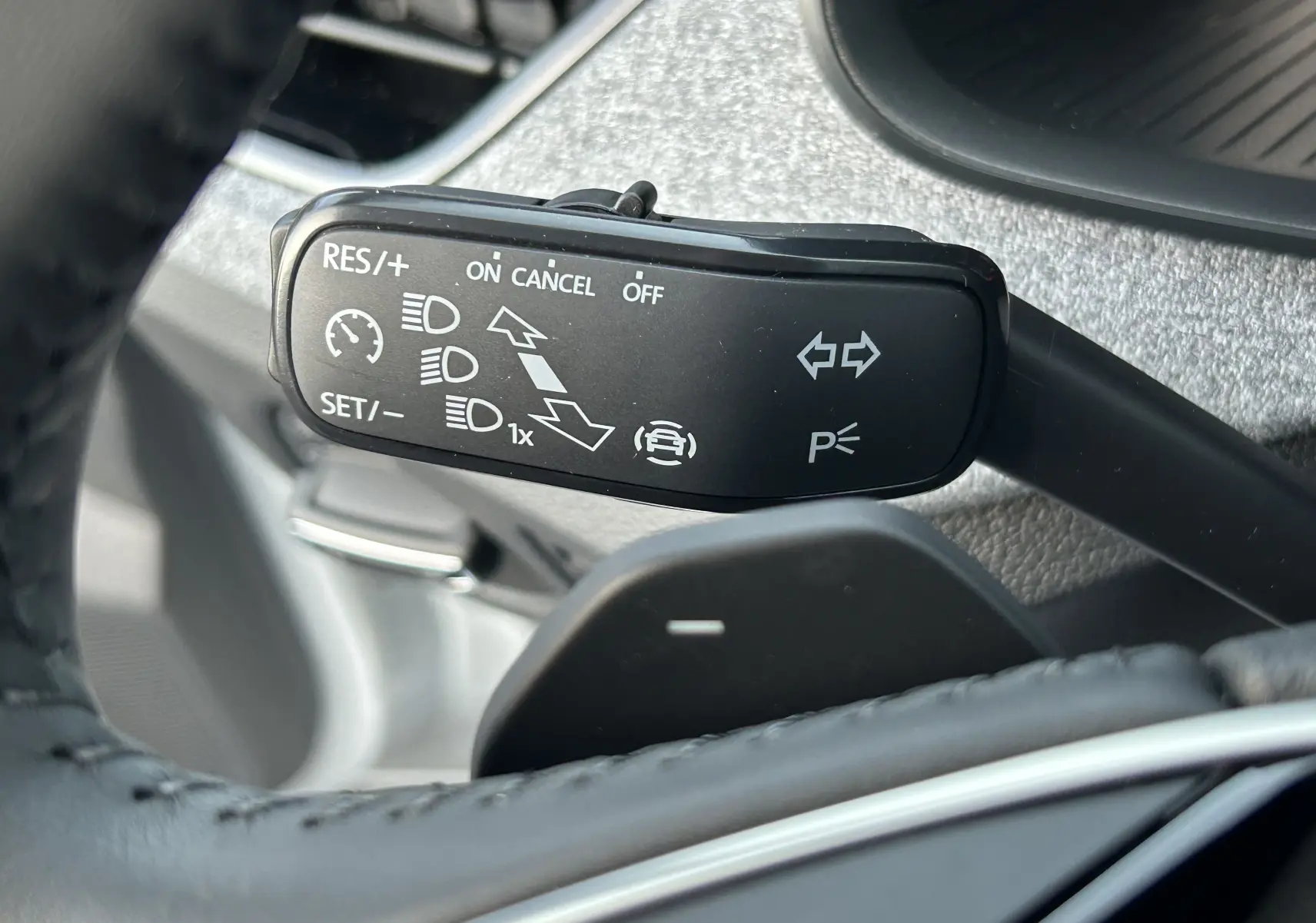 Gros plan sur la commande de régulateur de vitesse au volant d’un Skoda Kamiq gris argent 2025, intérieur tissu gris-noir.