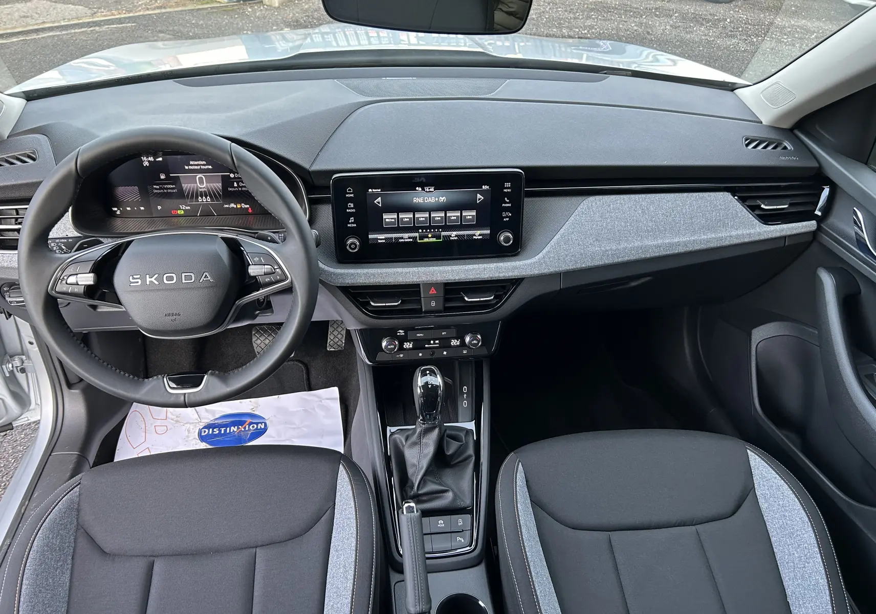 Vue intérieure avant du Skoda Kamiq 2025, tableau de bord gris noir avec écran tactile et volant multifonction.