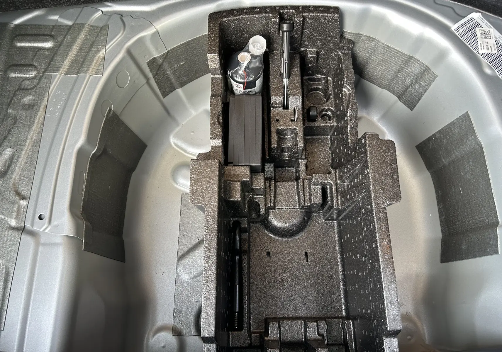 Vue en plongée du coffre à outils et rangement sous le plancher du coffre du Skoda Kamiq gris argent métal 2025.