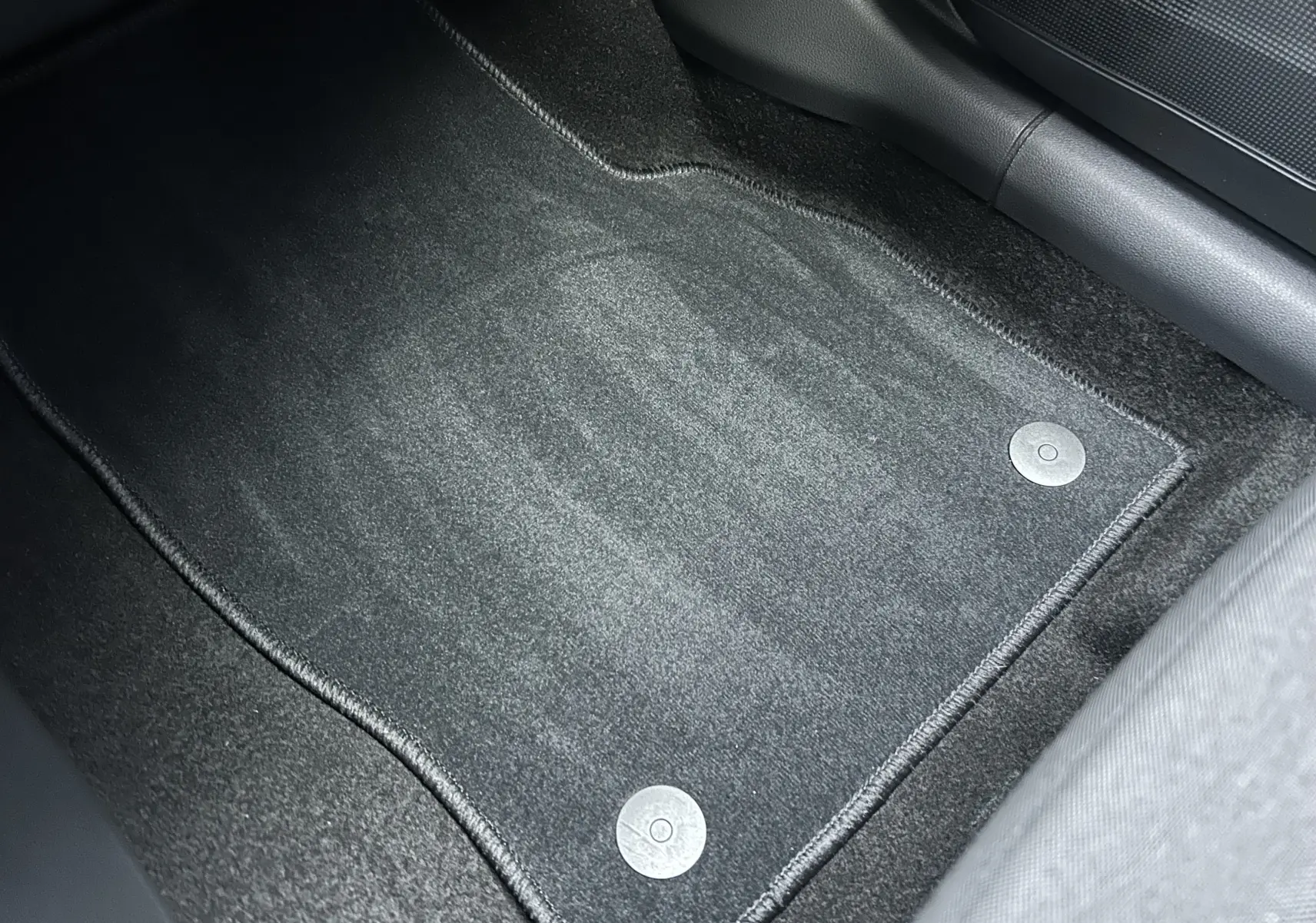 Vue rapprochée du tapis de sol gris foncé à fixation circulaire dans l'habitacle d'un Skoda Kamiq 2025 gris argent métallisé.