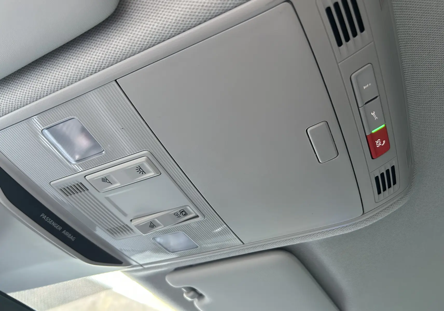 Vue intérieure du plafonnier gris clair du Skoda Kamiq 2025 avec commandes d'éclairage et bouton d'urgence rouge.