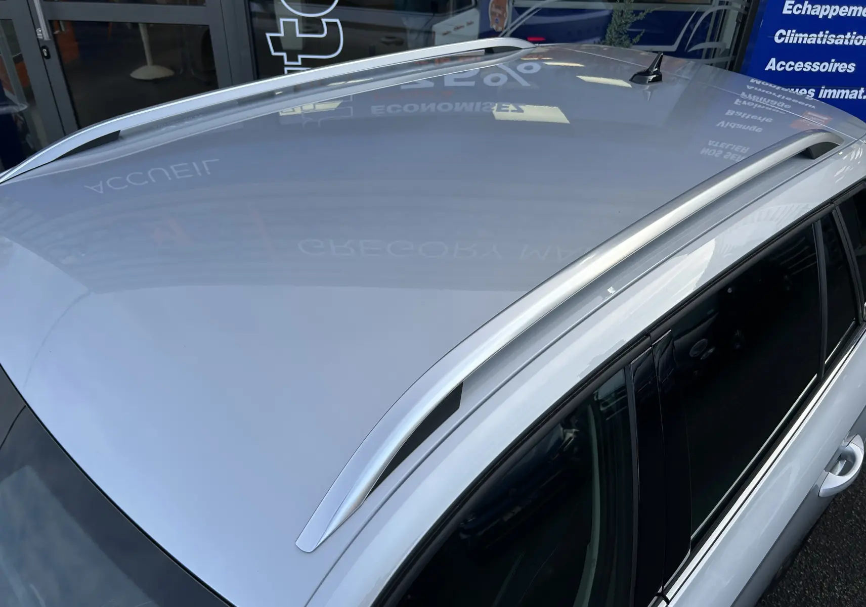 Vue en plongée du toit gris argent métallisé d'un Skoda Kamiq 2025 avec barres de toit et vitres teintées.