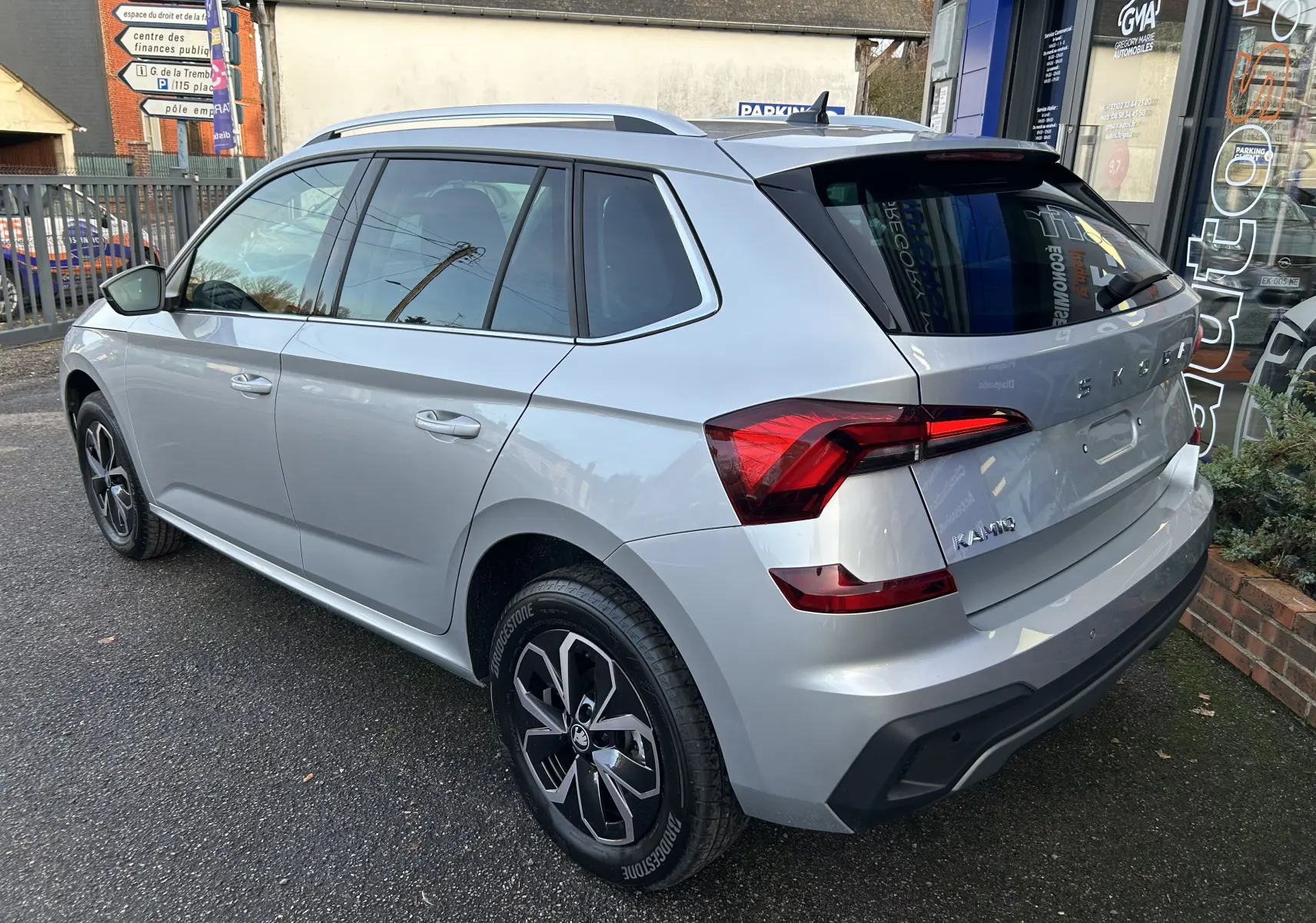 Vue 3/4 arrière droite d'un Skoda Kamiq gris argent métallisé avec feux arrière LED et jantes alliage noires.