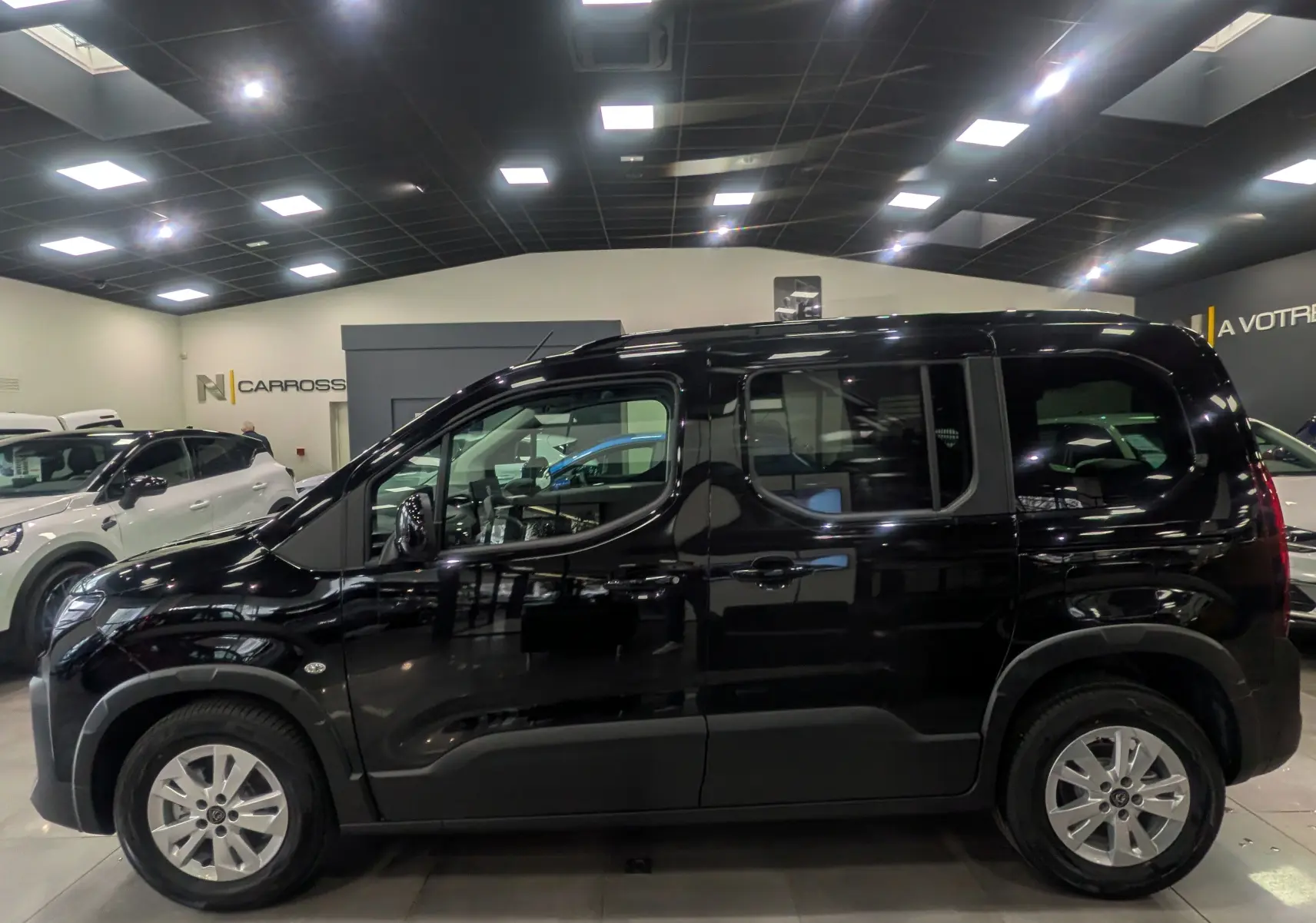 Profil côté gauche du Peugeot Rifter noir 2025 en version M BlueHDi 130 S&S EAT8 5 places, avec jantes alliage et vitres teintées.