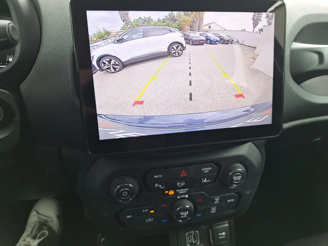 Vue intérieure centrée sur l'écran tactile montrant la caméra de recul d'une Jeep Renegade bleu 2024.