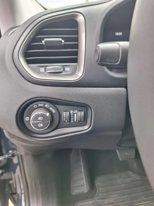Détail du tableau de bord côté gauche d’un Jeep Renegade bleu 2024, avec commandes des phares et ventilation.