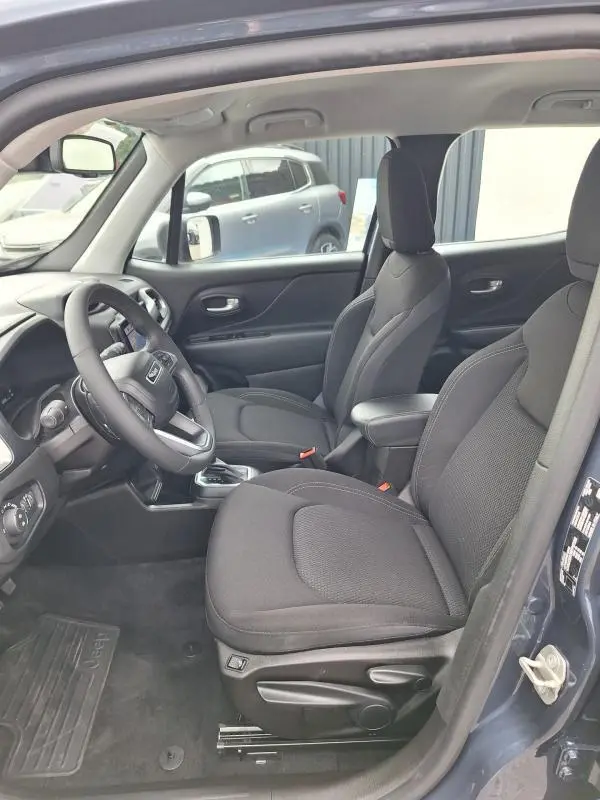 Vue intérieure côté conducteur du Jeep Renegade bleu 2024, montrant sièges noirs, volant et accoudoir central.