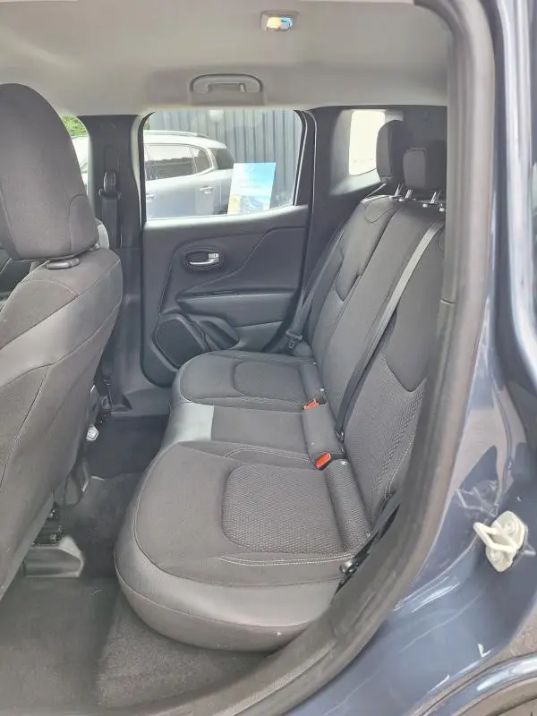Vue intérieure côté arrière droit du Jeep Renegade bleu 2024, montrant les sièges arrière en tissu noir et la portière ouverte.