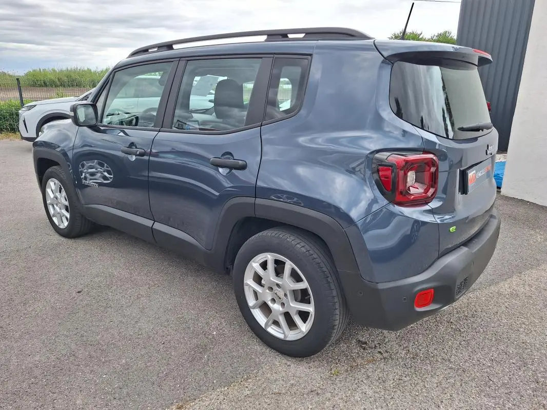 Vue 3/4 arrière droite d'un Jeep Renegade bleu 2024 avec barres de toit et jantes alliage 17 pouces.