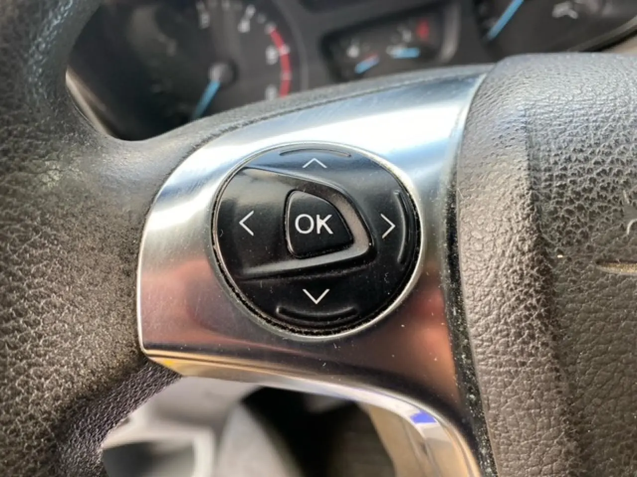 Gros plan sur les commandes au volant du Ford Transit Fourgon L3H2 2015, finition Ambiente, intérieur noir.