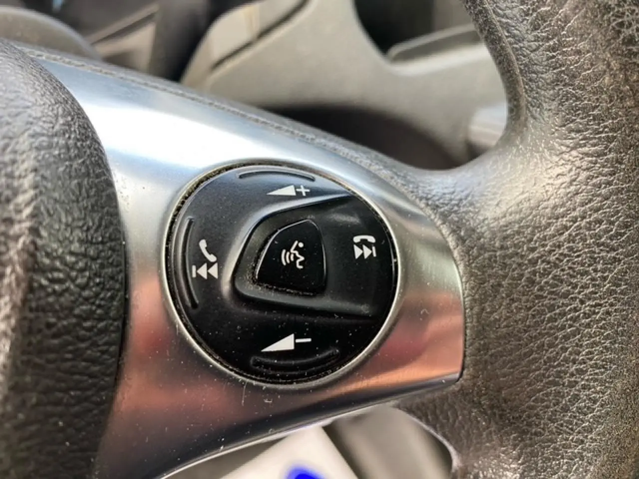 Gros plan sur les commandes audio et téléphone au volant du Ford Transit Fourgon L3H2 2015, intérieur noir.