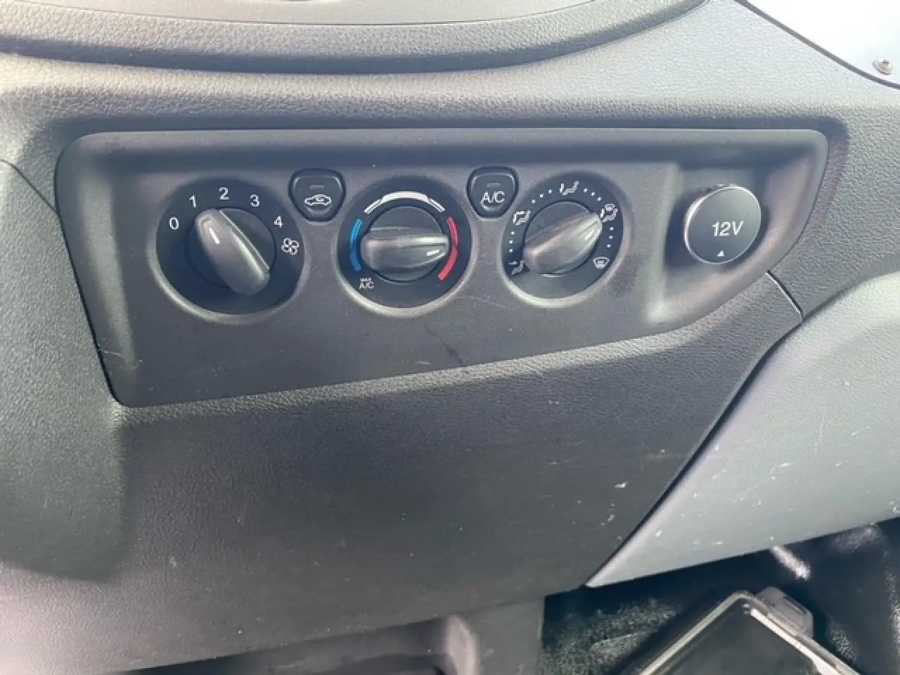 Détail du tableau de commande de climatisation et prise 12V dans un Ford Transit Fourgon L3H2 2015 noir.
