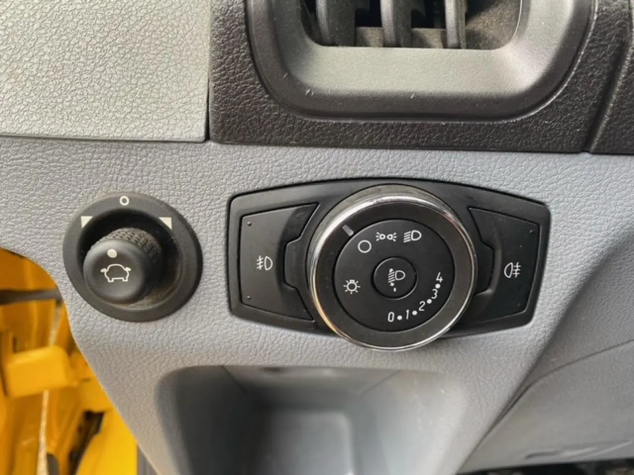 Gros plan sur les commandes d'éclairage et réglage du tableau de bord du Ford Transit Fourgon orange 2015.