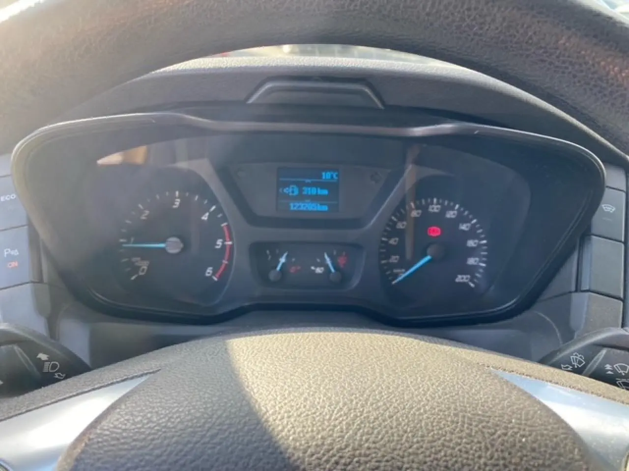 Vue rapprochée du tableau de bord du Ford Transit Fourgon orange 2015, affichant compteurs et écran digital.