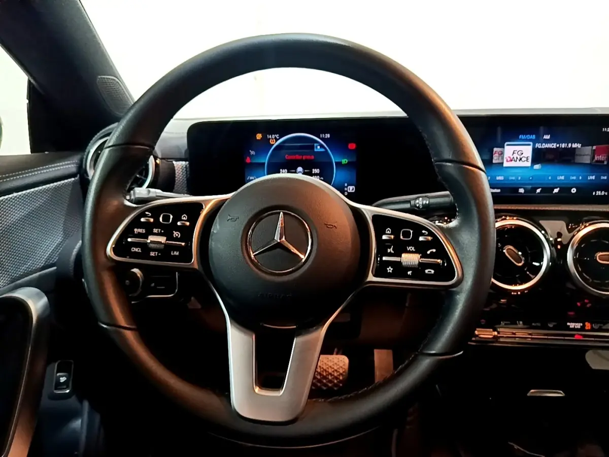 Vue rapprochée du volant cuir noir de la Mercedes CLA 180 d 2021 avec tableau de bord numérique et commandes intégrées.