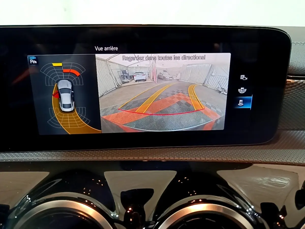 Affichage de la caméra de recul et des capteurs de stationnement sur l'écran tactile du tableau de bord d'une Mercedes CLA 180 d gris clair.